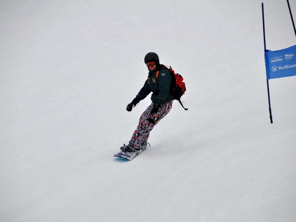 Snowboarder mit Rucksack zieht einen Schwung.